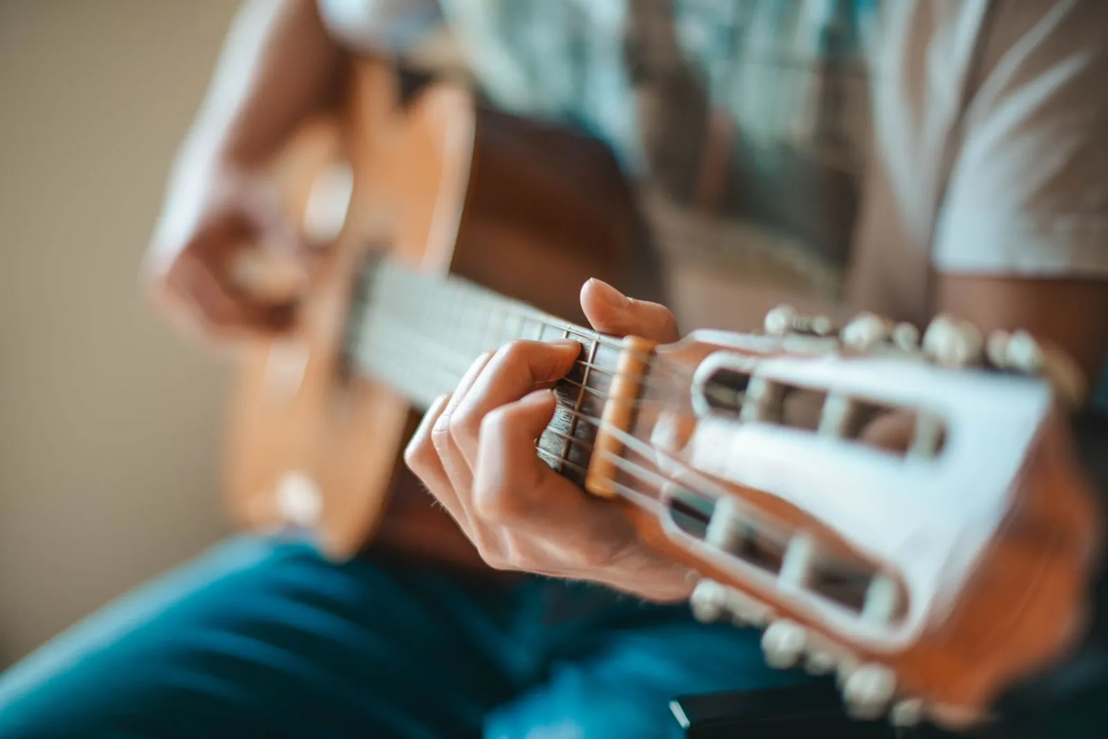 A person playing an acoustic guitar focusing on hand fretboard positioning.